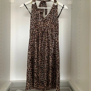 Leopardklänning med gulddetaljer - Måste retire denna baddieklänningen tyvärr 😔 så cool med mönstret och lite skimriga detaljer i tyget samt guldringarna. Man knyter i nacken. Så snygg när man är så solbrun. S men superstretchig
