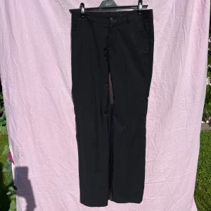 Svarta kostymbyxor från Tiger of Sweden - Klassiska svarta kostymbyxor från Tiger of Sweden med raka ben och midja med hällor för bälte. Snygg och stilren passform, perfekta till skjorta eller stickad tröja. Gjorda i ett mjukt och följsamt tyg som känns bekvämt hela dagen. W31 L32