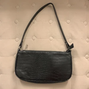 Svart axelväska  - Svart axelväska med silverfärgad dragkedja. Väskan har svart innerfoder. Aldrig använt, nytt skick💗