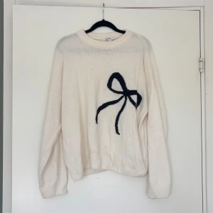 Vit stickad tröja med svart rosett - Superfin vit stickad tröja från Subdued med en stor rosett på framsidan. 