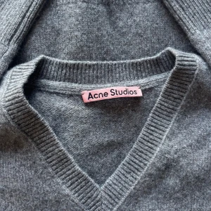 Grå v-ringad stickad tröja Acne Studios - Beige/brun stickad tröja från Acne Studios. Oversized i modellen. 70% bomull 30% Kashmir. Herrstorlek