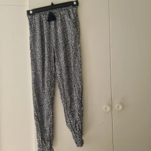 Blåa blommiga byxor  - Blå byxor med vitt blommigt mönster från Hampton Republic. Stretchig midja med smalare benslut. Storlek 152