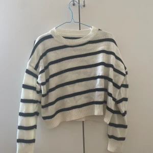 Vit och svart randig stickad tröja - Säljer en vit stickad tröja med svarta horisontella ränder. Tröjan har en rund halsringning, långa ärmar och en lite croppad passform. Den har tyvärr ingen lapp där det står vilket märke den är ifrån!❤️