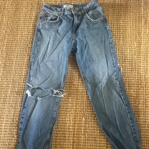 Blå jeans med hål vid knät - Midwaist raka blåa jeans med hål vid knät strl 34 från pull and bear