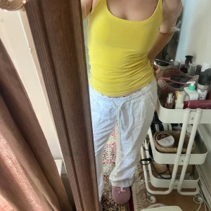 Gul linnetopp med smala axelband - Snygg gul linnetopp med smala axelband och figurnära passform. Perfekt för varma dagar och enkel att styla med jeans eller kjol. Mjuk och stretchig bomull som känns skön mot huden. Enkel, stilren design utan mönster eller detaljer. På sista bilden syns en liten fläck det är isåfall den ända defekten jag kan se! Linnet är annars i fint skick och man tänker inte på fläcken så mycket!🤎🍁