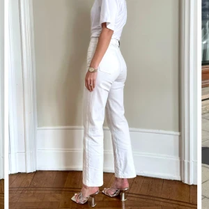 Vita raka jeans från Sanne Alexandra  - Snygga vita jeans från Sanne Alexandra med raka ben i modellen cropped stretch jeans. Klassisk femficksmodell med stilren design och läderpatch bak i midjan. Endast använda ett par timmar då jag köpte två storlekar och valde den andra. Storlek 38. Nypris är 995 kr.