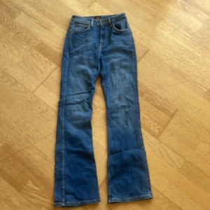 Lee Breese Boot blå bootcut jeans - Snygga blå Lee Breese Boot jeans med klassisk bootcut passform och fem fickor. Jeansen har normal midja och är tillverkade i slitstarkt bomullsdenim. Perfekt för dig som gillar en tidlös look med lite utsvängda ben. Ikonisk Lee-logga på bakfickan och läderpatch i midjan.