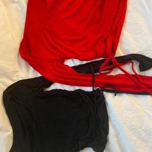 Röd och svart croppad topp med snörning - Två långärmade croppade toppar i ribbad bomull, en röd och en svart. Båda har snörning i sidorna som man kan knyta till rosetter. 60kr st men båda för 150k