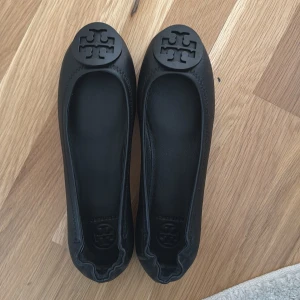 NYA svarta ballerina från Tory Burch EU 37   - minnie powder coated logo- ballerinaskor-perfect black från tory burch. Skorna är i mjukt fårskinn och fodret är i läder. Helt nya och oanvända. Har dessa i en större storlek och asså de är så bekväma och passar med allt😍 Ordinarie pris är 3275kr på zalando. 