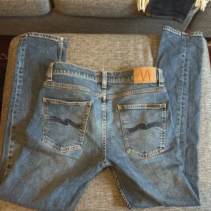 Nudie Jeans Lean Dean Blue Vibes 30/32 - Säljer ett par Nudie Jeans i deras populäraste modell, Lean Dean, i tvätten Blue Vibes. Klassiska blå jeans med blåa och oranga sömmar, fem fickor och snygg vågdetalj på bakfickorna. Tillverkade i 98% bomull och 2% elastan för lite stretch. Perfekt passform och stilren look.
