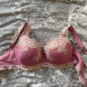 Rosa bh intimissmi - Supersöt rosa bh med broderade blommor i beige spets. Axelbanden är dekorerade med spets och det finns en liten rosett framtill. Storlek 75C men små i storlekarna skulle säga 75B.