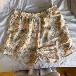 Blommiga shorts från Made in the Shade - Superfina shorts från Made in the Shade i storlek S. De är persikofärgade med blommigt mönster i ljusgult och svart. Mjukt och lätt material med resår i midjan för skön passform. Knappt använda. 