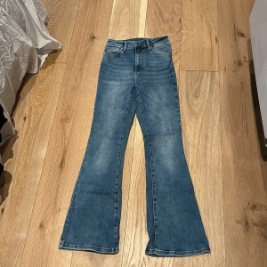 Blå Peachy Flare jeans - Snygga blå Peachy Flare jeans från bikbok med klassisk femficksdesign och utsvängda ben. Jeansen har lite hög m midja och är tillverkade i mjukt denim som är stretchig, med lätt tvättad look. 