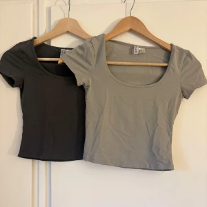 2 croppade toppar från h&m XS - Säljer två croppade toppar från h&m i storlek XS. En är mörkgrå och den andra är ljusgrå, båda med rund halsringning och korta ärmar. Perfekta att matcha med jeans eller kjol för en enkel och clean look.