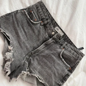 Grå jeansshorts med fransig kant, köpta ifrån Zara. - Perfekta gråa jeansshorts till sommaren, de är i hög midja men kan bäras med nedvikt midja. Storlek 36 och de är ifrån ZARA. 