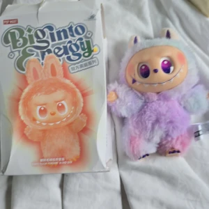 Labubu⭐️🎀 - Bilderna visar en färgglad och fluffig figur från Pop Mart, kallad Biginto Energy. Det är en samlarleksak med stora, glittrande ögon och ett gulligt monsterutseende. Perfekt för dig som gillar unika och söta figurer att ha i bokhyllan eller som dekoration.