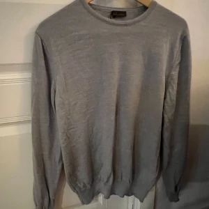 Grå stickad tröja från Stenströms - Snygg grå stickad tröja från Stenströms med rund hals och långa ärmar. Tröjan har en enkel och clean look med ribbade muddar vid ärmslut och nederkant. Perfekt för dig som gillar stilrena och klassiska plagg. Passar M/S