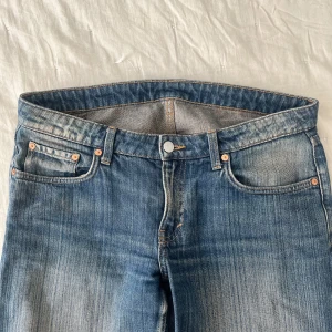 Blå raka jeans från Weekday - Snygga blå jeans med klassisk tvätt och raka ben. Jeansen har fem fickor, ljusa slitningar och kontrastsömmar. Passar perfekt till en avslappnad stil och är tillverkade i slitstarkt denimtyg.