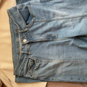 Ljusblå wide jeans i storlek 38 - Säljer ett par ljusblå jeans med breda ben och klassisk femficksdesign. Jeansen har hög midja, raka sömmar och är tillverkade i mjukt denimtyg. Perfekta för en avslappnad och trendig look.