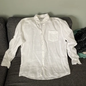 Vit Gant  linneskjorta med bröstficka - Klassisk vit skjorta i linne med lång ärm och en bröstficka. Skjortan har knappar hela vägen framtill och en avslappnad passform. Perfekt för en stilren och fräsch look.