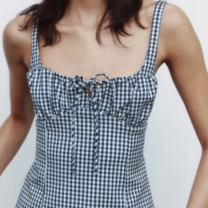 Rutig blåvit topp med snörning - Supersöt klänning i blåvitt rutigt mönster med smala axelband och snörning framtill vid bysten. Figurnära passform och perfekt för varma dagar. Ger en fräsch och trendig vibe. (Kan även skicka bilder privat)