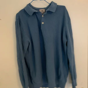 Blå pikétröja från H&M, regular fit - Klassisk blå pikétröja från H&M i regular fit. Tröjan har krage, knäppning med två knappar och långa ärmar. Perfekt för en chill och stilren look. Materialet känns mjukt och bekvämt mot huden.
