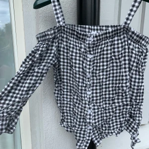 Somrig rutig offshoulder blus med ärmar 🤍 - Supersöt svartvit rutig blus med offshoulder och smala axelband. Perfekt att ha som fest topp eller vanlig vardags tröja!❤️