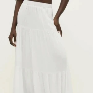 Vit långkjol i bomull - Säljer en flowy vit långkjol med resår i midjan. Kjolen är i tunn bomull och har en luftig känsla, perfekt för varma dagar. Stilren och enkel design som ger en chill vibe.