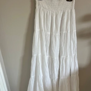 Vit långklänning från Nelly - Luftig vit långklänning från Nelly med smock upptill och volangiga lager. Aldrig använd. Vill du ha fler bilder så fixar jag.