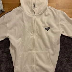 Vit hoodie från Prada med dragkedja - Snygg vit hoodie från Prada med hel dragkedja framtill och klassisk huva. Storlek xl med passar dom som har L 