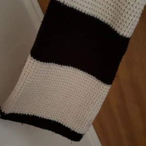 Randig stickad tröja i svart och vitt - Säljer en oversized stickad tröja med breda svarta och vita ränder. Tröjan har lång ärm och grovstickad struktur som ger en cool och avslappnad vibe. Perfekt för dig som gillar statement-plagg och vill sticka ut lite extra.