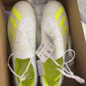 Adidas X 18.1 vita fotbollsskor - Nytt pris kan diskuteras                                  Snygga Adidas X 18.1 fotbollsskor i vitt med neongula detaljer och klassiska tre ränder på sidan. Skorna har låg vikt, plös i syntetmaterial och mönstrad sula för bästa grepp på planen. Insidan är fodrad i neongult och ovandelen är i mesh och syntet. 