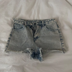 Ljusblåa jeansshorts med fransig kant - Snygga ljusblå jeansshorts med hög midja och rå, fransig kant nertill. Klassisk femficksmodell med bälteshällor och dragkedja med knapp. Perfekta för varma dagar, använt några gånger för länge sen, fina short trots att de är från shein 