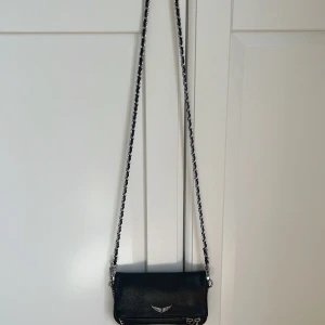 Zadig & Voltaire rock nano väska - Säljer denna fina och trendiga Zadig & Voltaire väskan i modell rock nano då den tyvärr inte kommer till användning längre. Man får med ett längre läderband (bild 1) och en kortare kedja (bild 2). Väskan är i super bra skick, nypris ungefär 2900 kr men säljer för 800kr dock går pris att diskutera! 