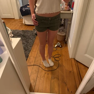 Olivgröna shorts med knappar - Snygga olivgröna shorts med låg midja och knappar framtill. Klassisk modell och korta ben. Perfekta för varma dagar och enkel att matcha med olika toppar.