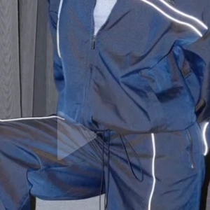 Blå vindjacka från Luxe To Kill - Säljer en blå vindjacka från Luxe To Kill med vita reflexdetaljer längs dragkedja och ärmar. Jackan har dragkedja framtill, hög krage och ett litet metallmärke på bröstet. Perfekt för dig som gillar sportig stil.