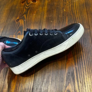 Svarta lanvins uk6 bara skor! - Snygga svarta sneakers med ovandel i mocka och en glansig, lackad tå. Skorna har snörning och en vit, platt gummisula som ger en klassisk look. Perfekta för dig som gillar stilrena och moderna skor skorna tvättas såklart innan dom postas och inga större repor på lacktån utan box bara skor 