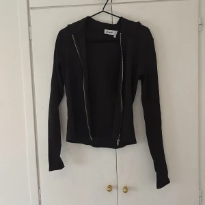 Svart tröja med dragkedja - från Weekday - Svart tröja i tjockare material ifrån Weekday med dragkedja framtill och huva. Den är i storlek M men är ganska liten för storleken. Har använt 1 gång. Nyskick.
