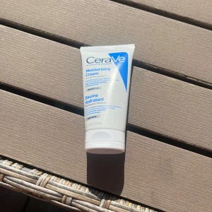 CeraVe Moisturising Cream - Fuktgivande ansiktskräm från CeraVe i en vit och blå tub. Innehåller ceramider och hyaluronsyra som återfuktar och stärker hudbarriären. Passar för daglig användning och är parfymfri. Tuben är smidig att ta med i väskan.