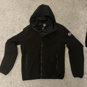 Svart hoodiejacka från Colmar - Svart hoodiejacka från Colmar med dragkedja framtill och två fickor med dragkedja. Jackan har en huva och Colmar-logga på vänster ärm. Perfekt för en stilren och sportig look. Kvitto finns!! Nypris: 1699 Mitt pris: 700