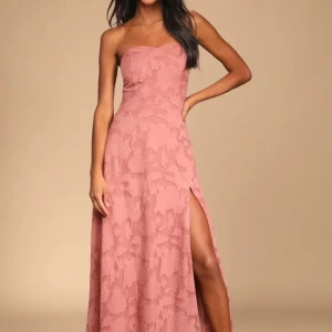 Rosa axelbandslös långklänning med slits - Säljer en romantisk rosa långklänning med axelbandslös design och slits framtill. Klänningen har ett blommigt mönster och en snygg öppen detalj i ryggen. Perfekt för bal eller fest! 💗🌸 (helt ny med prislapp kvar)