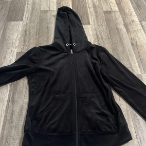 Svart hoodie i velour från Gina Tricot - Mjuk och skön svart hoodie i velour från Gina Tricot. Tröjan har dragkedja framtill, huva med snörning och två fickor. Perfekt för en avslappnad stil och passar bra till vardags.