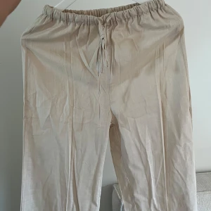Beiga linnebyxor  - Säljer ett par beiga linnebyxor med avslappnad passform. Byxorna har raka långa ben och är perfekta för varma dagar. Lätta och luftiga.
