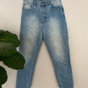 Ljusblå Nora jeansbyxor från Dr Denim - Säljer ett par klassiska ljusblå jeansbyxor från Dr Denim, modell Nora Regular Blue. Byxorna har hög midja, raka ben och avslappnad passform i mom-jeans fit. De har en snygg tvättad look med ljusa partier framtill och baktill.