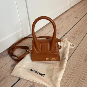 Jacquemus Le Chiquito väska  - Helt ny och äkta Jacquemus Le Chiquito Brown, som är slutsåld på hemsidan (550 euro). Köpt på Jacquemus, tyvärr inget kvitto då födelsedagspresent. Aldrig använd.  ”12 x 9 cm. 100% Cowskin.”. Dustbag medföljer, samt etiketten finns fortfarande kvar😊