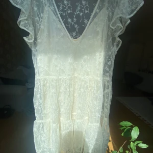 Vit spetsklänning med volangärmar från Zara - Vit klänning i spets från Zara med v-ringning och volangdetaljer vid ärmarna. Perfekt för somriga tillfällen, avslutningar, student! Storlek M men passar mig som vanligtvis har S perfekt. Endast använda 1 gång