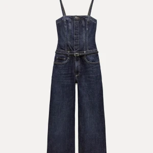 Mörkblå jeans jumpsuit med bälte - Snygg mörkblå jeans jumpsuit med smala axelband och markerad midja med bälte. Vida ben och klassiska jeansfickor framtill. Helt oanvända med lappen på. 