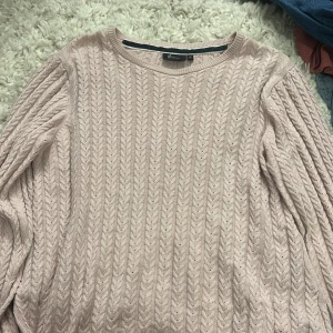 Ljusrosa stickad tröja - Säljer en ljusrosa stickad tröja från Jeansro i storlek S. Tröjan har ett snyggt flätmönster över hela och rund halsringning. Perfekt för dig som gillar mjuka och mysiga plagg med lite extra stil. Långärmad och passar till många olika looks.