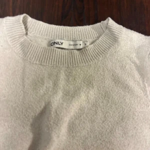 Vit stickad tröja från ONLY - Säljer en vit stickad tröja från ONLY med rund hals och ribbade muddar. Tröjan har en enkel och clean look med korta ärmar som ger en fräsch vibe. Perfekt för dig som gillar stilrena plagg och vill ha något som funkar till många outfits.