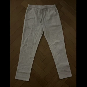 Vita och marinblå linnebyxor - Två par byxor i klassisk rak modell, två par vita och ett par marinblå. Båda har elastisk midja med dragsko och är tillverkade i svalt linne. Perfekta för chill dagar eller när du vill ha en clean och enkel look.